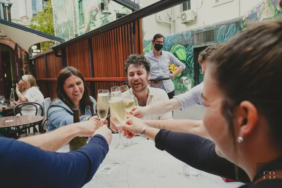 A group of people raising their glasses and saying cheers during a tour of Melbourne's laneways